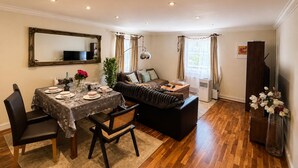 Un comedor con una mesa dispuesta para cuatro personas, un sofá y un televisor.