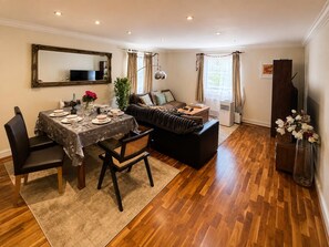 A dining area with a table set for four, a sofa, and a television.