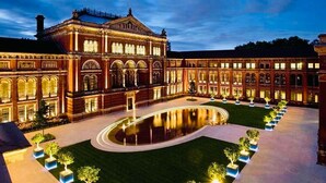 Un gran edificio iluminado, con un patio central y una piscina reflectante.
