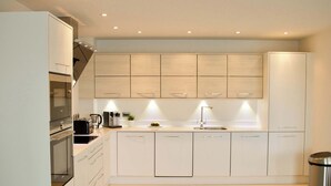 A modern kitchen with white cabinetry, a built-in oven, and a stainless steel trash can. - Luxurious Central Edinburgh Apartment - Sleeps 6 (Edinburgh)