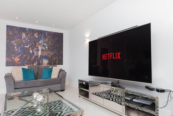A modern living room with a large flat-screen TV, a sofa, and a coffee table.