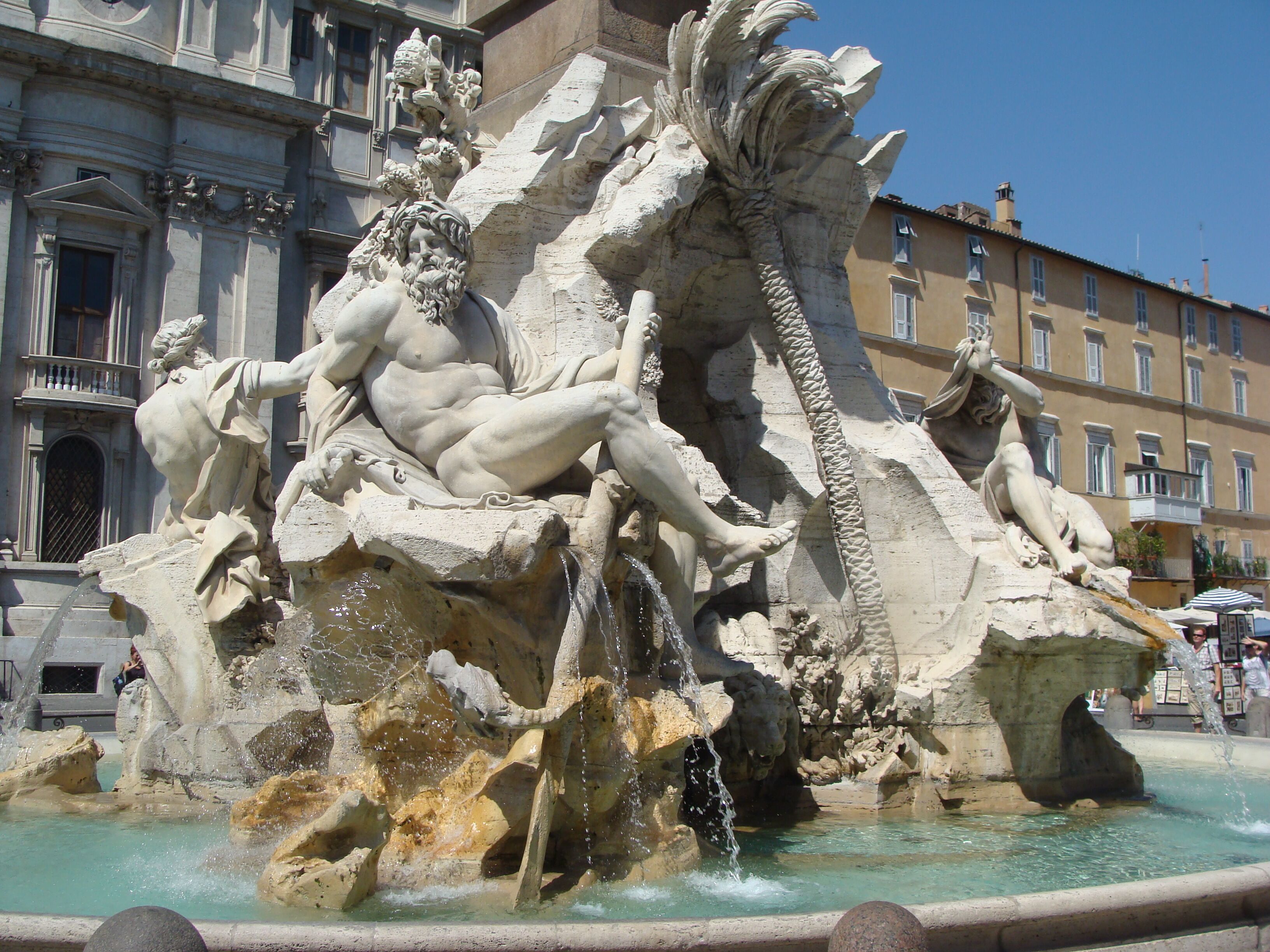 Ein großer, aufwendiger Brunnen mit zahlreichen Statuen vor klassischer Architektur.