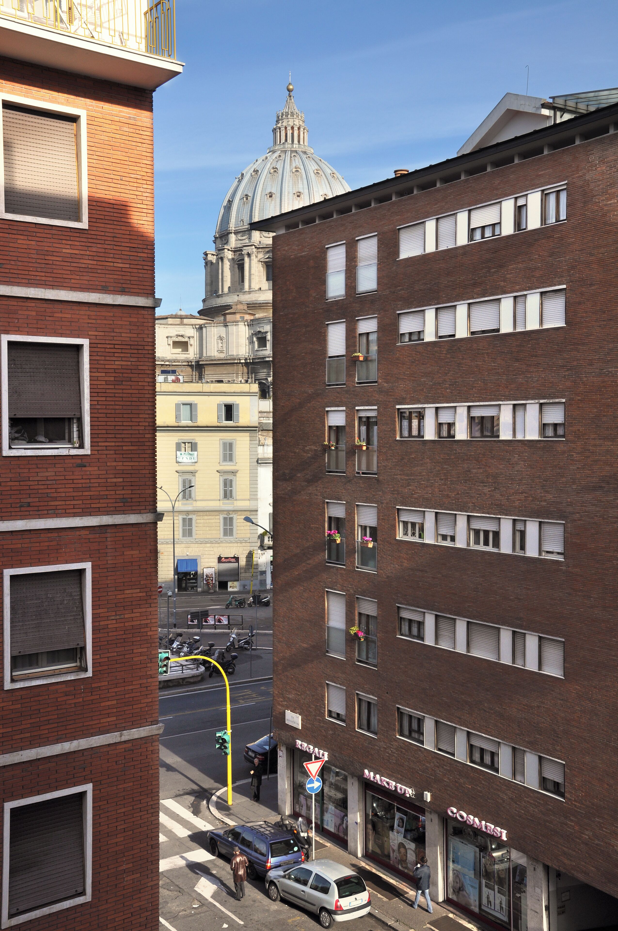 Straßenansicht mit einem markanten rotbacksteingebäude, einer Kuppel im Hintergrund und einem Laden mit einem Schild.