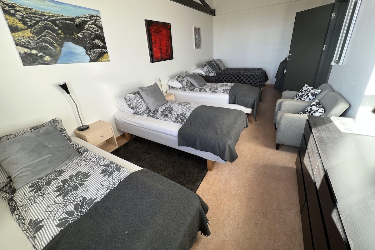 A compact hotel room with two single beds, a sofa, and a desk.