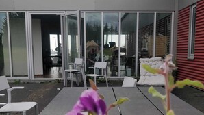 An outdoor patio area with a modern design, featuring a long table and several chairs. - Godaland Guesthouse (Rangárþing eystra)