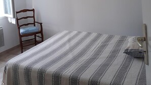 Ein Schlafzimmer mit einem Bett, einem Sessel und zwei Bildern an der Wand.