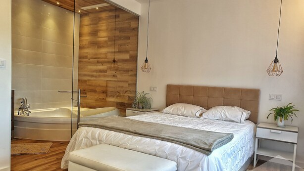 Une chambre moderne avec un grand lit, une baignoire séparée et un mur d’accent en bois.