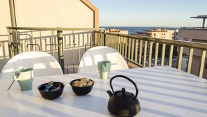 Ein Balkon mit einem Tisch, gedeckt für ein Frühstück, inklusive einer Schüssel mit Essen, einem Teekessel und zwei Tassen.