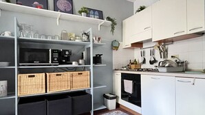 Une cuisine avec des meubles blancs, un four à micro-ondes, une cuisinière et un tapis à motifs.