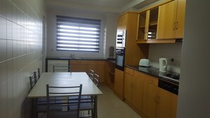 Une cuisine de taille réduite comprenant une table à manger, des chaises, un évier, une cuisinière et des armoires en bois.