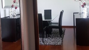 Une pièce dotée d’un grand miroir qui reflète un bureau, une chaise et une petite table sur laquelle est posé un vase de fleurs.
