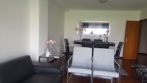 Un salon avec un canapé gris, une table à manger avec des chaises et un miroir au-dessus de la table.