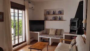 Ein Wohnzimmer mit Fernseher, einer Couch, einem Holztisch und einem Kamin.