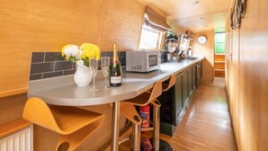 Una cocina con detalles de madera, microondas, pileta y ventana con cortinas.
