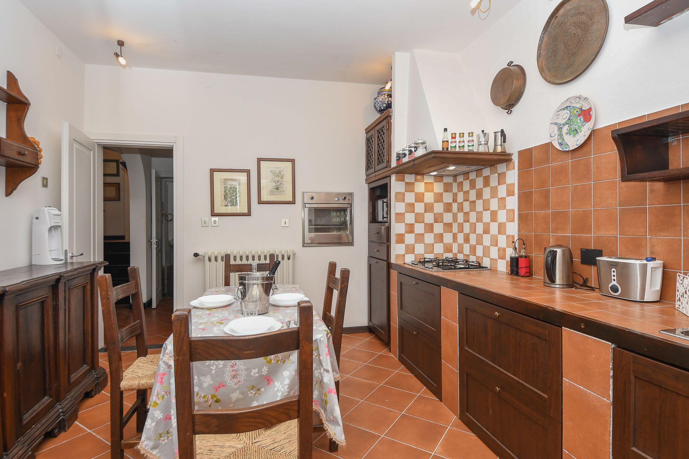 A kitchen with a dining table, chairs, a stove, oven, and various kitchen appliances.