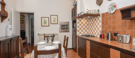 A kitchen with a dining table, chairs, a stove, oven, and various kitchen appliances.