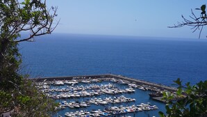 Ein Yachthafen mit zahlreichen vertäuten Booten, umgeben von blauem Himmel und ruhiger See.