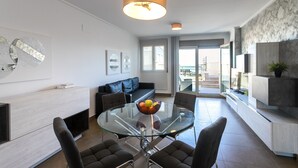 Un salón moderno con una mesa de comedor de cristal, sofás oscuros y un diseño minimalista.