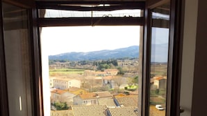 A window with a view of a town, a potted plant on the windowsill, and a metal railing. - Charming, centrally located house close to Carcassonne, perfect for families! (Capendu)