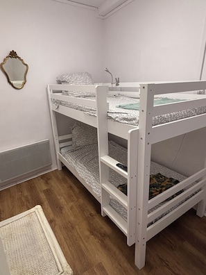 Una cama litera con ropa de cama estampada y un espejo en la pared.