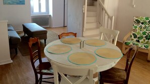 A dining area with a round table, four chairs, and a bench. There is a staircase leading to an upper floor. - Charming, centrally located house close to Carcassonne, perfect for families! (Capendu)