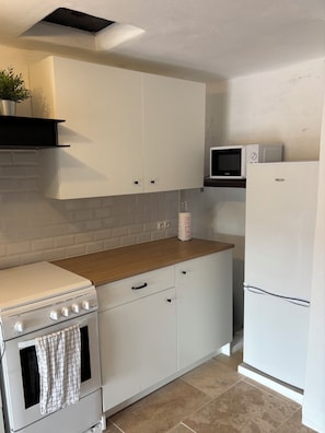 Une cuisine avec des meubles blancs, une cuisinière, un four à micro-ondes et un réfrigérateur.