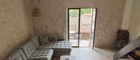 A living room with a sectional sofa, a small round table, and a staircase leading to an outdoor area.