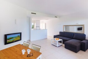 A modern living room with a TV, sofa, coffee table, and dining table.
