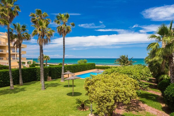 A resort with a pool, palm trees, and a view of the ocean.