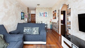 A living room with a sofa, a flat-screen TV, and a stone wall. - Front line beach apartment with wifi and air conditioning (Arona)