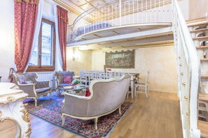Ein geräumiges Wohnzimmer mit hoher Decke, aufwendigen Möbeln und einer Treppe, die in eine obere Etage führt.