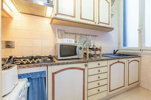 A kitchen with a gas stove, a microwave, and a wine rack. - Italian Experience - Suite Medici (Florence)