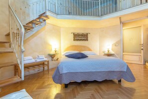 Ein Schlafzimmer mit einem Bett, einem Nachttisch, einer Lampe, einem Bild an der Wand und einer Treppe.