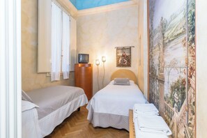Un dormitorio con dos camas, un aparador de madera, un televisor y un cuadro en la pared.