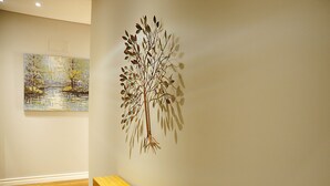 A room with a wooden bench, a wall-mounted tree sculpture, and a painting of a landscape. - Renovated apartment with private exterior in the center of Setúbal (Setúbal)
