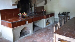 A traditional kitchen with a brick oven, a wooden table, and a tiled backsplash. - Noble villa for 16 people, with park and pool in Tuscany  (Nocchi)