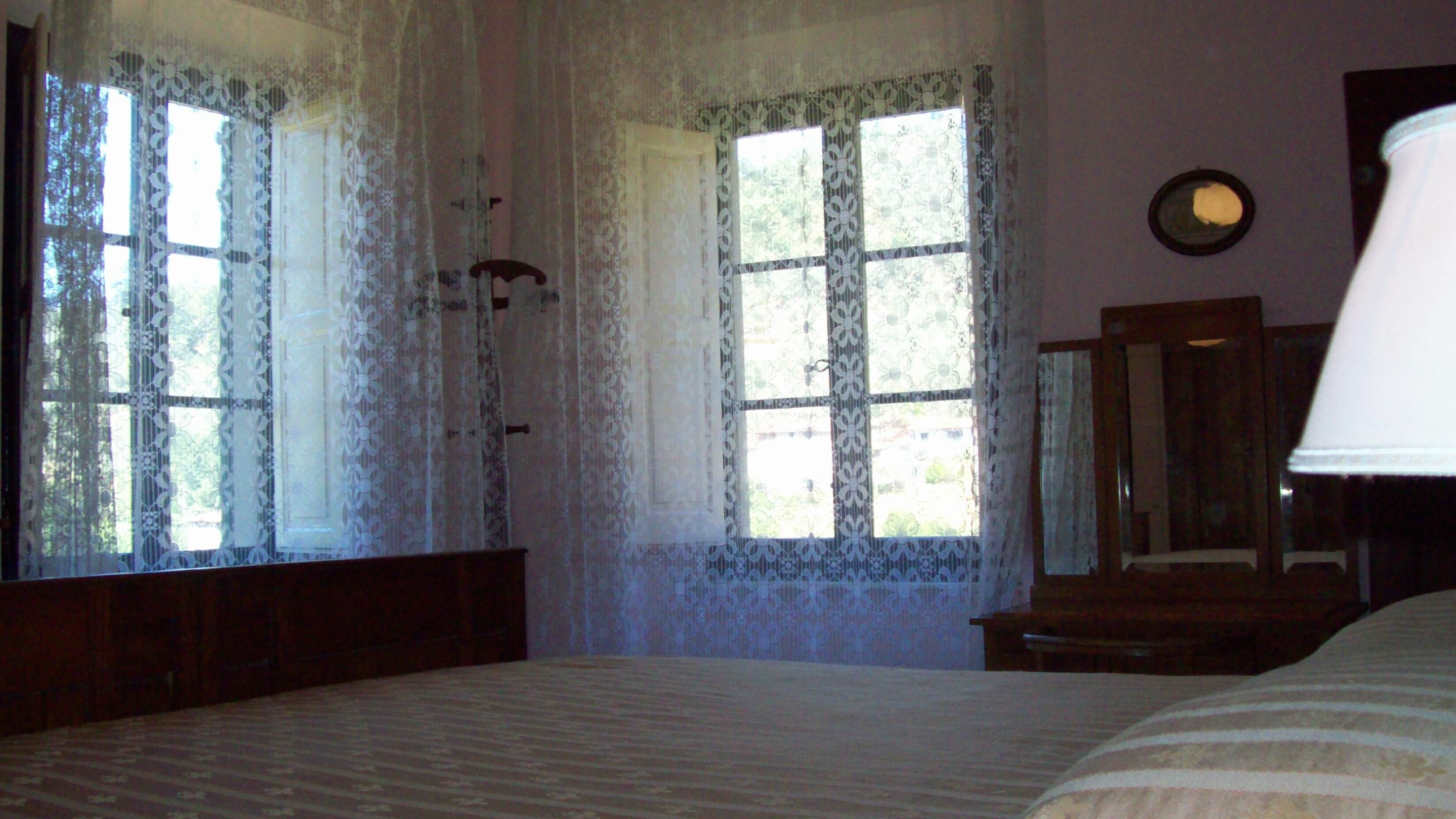 Un dormitorio con una cama grande, cortinas de encaje y un espejo en la pared.