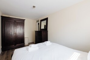 A hotel room with a large wardrobe, a mirror, and a neatly made bed with towels. - Bright 1 BDR Apartment with Private Terrace (London)