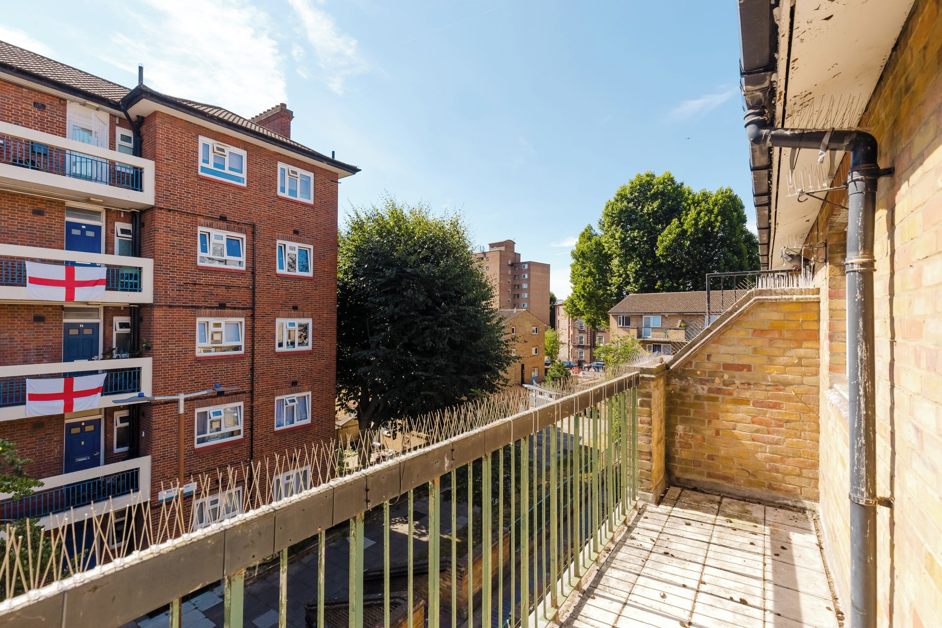A residential building with multiple windows and balconies, a wooden fence, and a clear sky.