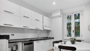 A modern kitchen with white cabinets, a dishwasher, and a dining area with a table and chairs.