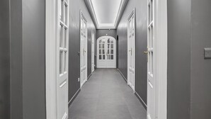 A hallway with grey walls, white doors, and a tiled floor.
