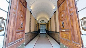 Un pasillo con puertas de madera y suelo de baldosas, que conduce a una puerta de cristal al final.