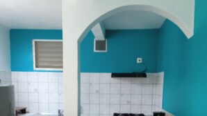 Une cuisine avec un mur d’accent bleu, des carreaux blancs, une cuisinière à gaz et deux tabourets.
