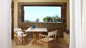 Un coin repas agrémenté d’une fenêtre en arc de pierre, d’une table et de quatre chaises.