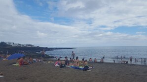 Une plage où des gens se prélassent au soleil et se baignent.