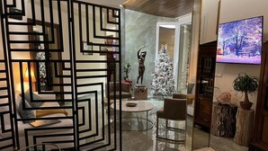 A modern living room with a geometric black partition, a white sofa, a round coffee table, and a Christmas tree. - Atticus Luxury Penthouse with Stunning Terrace  (Roma)