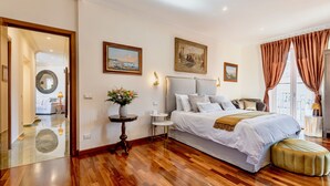 A spacious bedroom with a large bed, a wooden floor, and a view of the outdoors through a window with curtains. - Atticus Luxury Penthouse with Stunning Terrace  (Roma)
