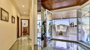 A modern hotel interior with a marble floor, a statue, and a glass door leading to a balcony with a view. - Atticus Luxury Penthouse with Stunning Terrace  (Roma)
