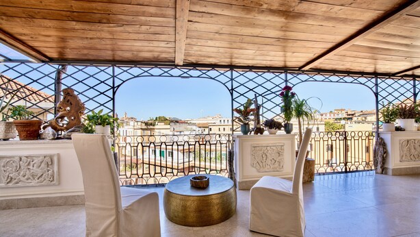 An outdoor seating area with white chairs and a round table, overlooking a cityscape. - Atticus Luxury Penthouse with Stunning Terrace  (Roma)