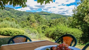 A table with a fruit bowl and chairs, overlooking a lush green landscape with hills and trees. - House with private pool at 2,8 km from Castiglione di Garfagnana. Panoramic view (villa collemandina)
